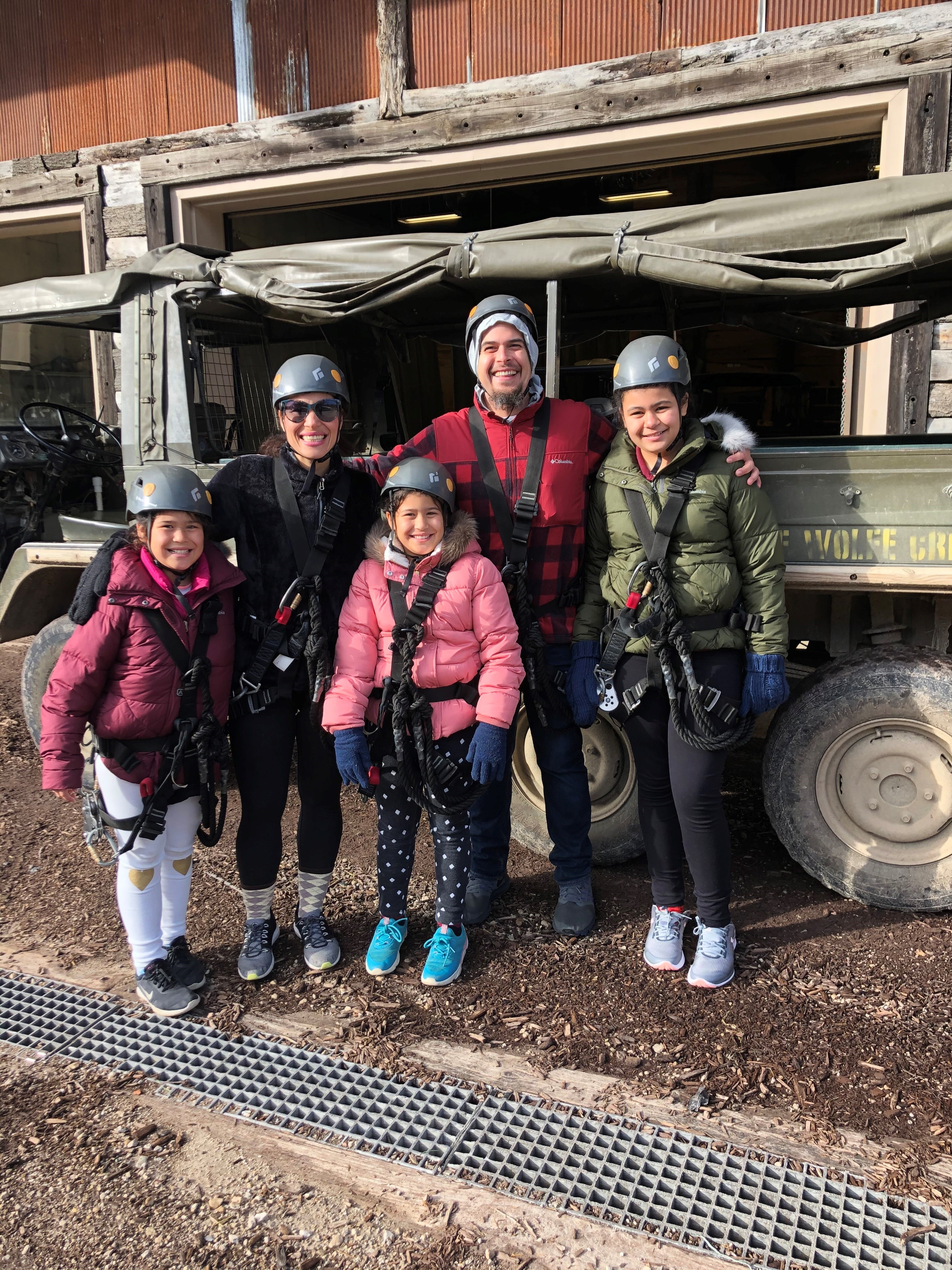 Family in coats and helmets next to off-road vehicle
